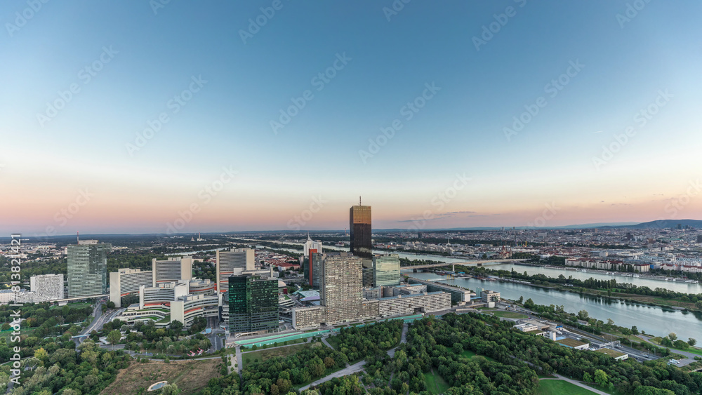 Obraz premium Aerial panoramic view over Vienna city with skyscrapers, historic buildings and a riverside promenade day to night timelapse in Austria.