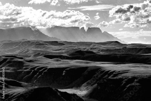 Dramatic black and white view of the mountains and valleys of the Drakensberg mountains with some of the iconic peaks and cliffs rising in the background