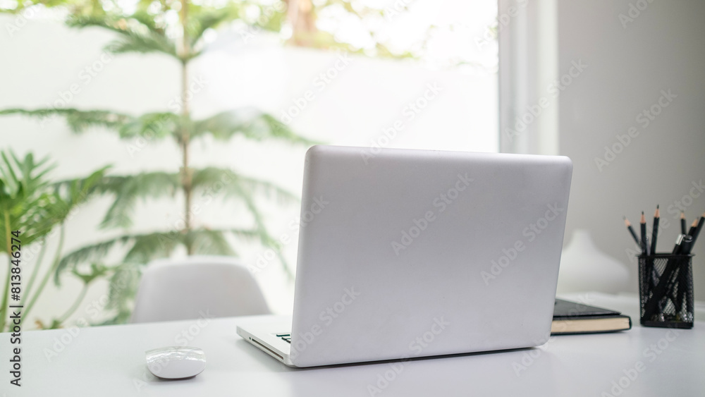 Laptop computer on white table near window with view of garden. Laptop computer on white table near window with view of garden.