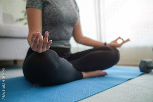Pretty young woman practicing yoga in living room. Mindfulness and healthy lifestyle concept.