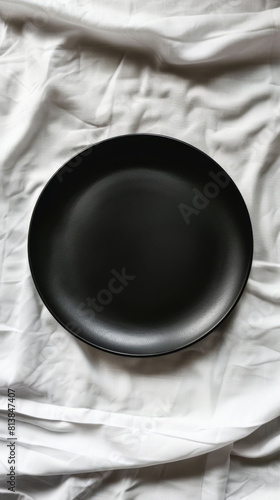 Black plate on a wrinkled white cloth background photo