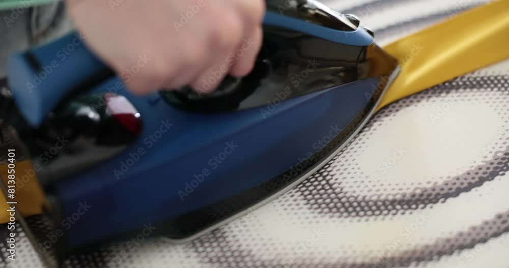 Housewife irons yellow belt with hot steam. Woman taking care of clothes at home Housewife irons yellow belt with hot steam. Woman taking care of clothes at home