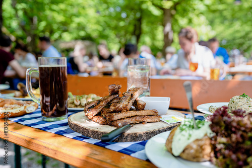 Genießen im Biergarten: Spareribs und dunkles Bier unter grünen Bäumen