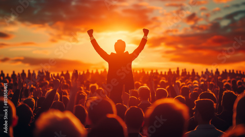 Crowd of people at a concert or festival with raised hands in front of bright stage lights photo