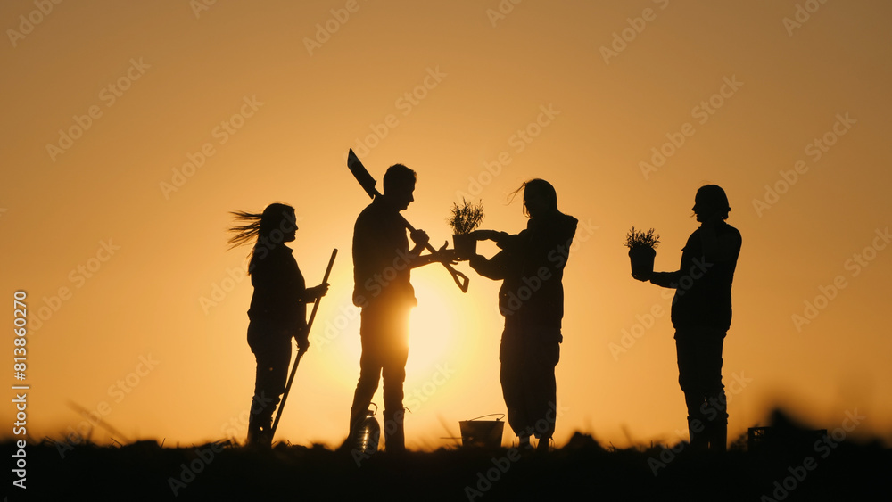 A group of farmers chatting in a field at sunset. With them their work equipment and seedlings A group of farmers chatting in a field at sunset. With them their work equipment and seedlings