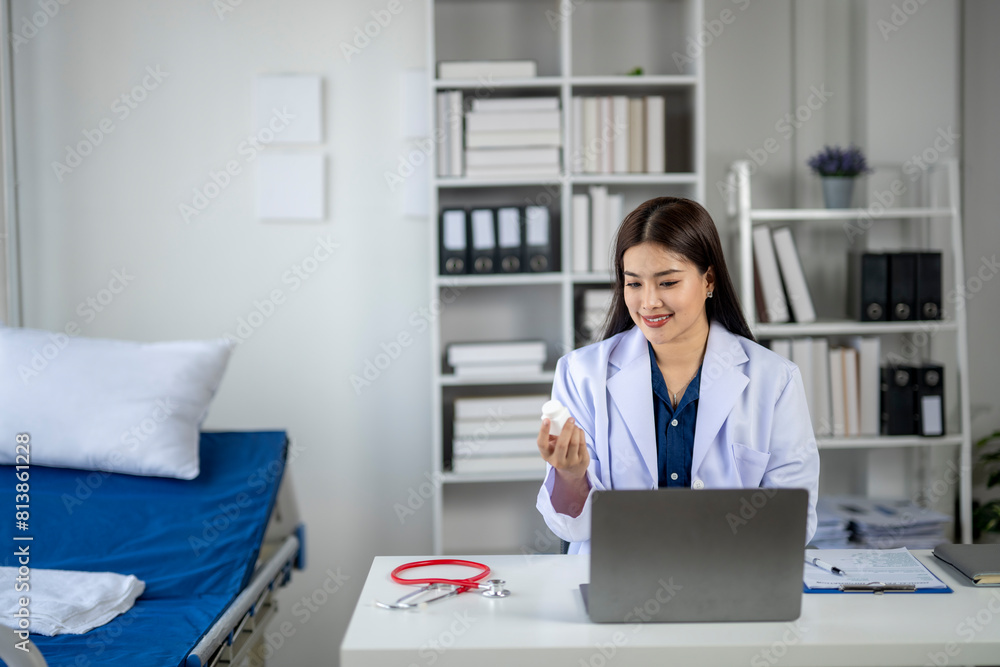 A woman in a white lab coat is sitting at a desk with a laptop A woman in a white lab coat is sitting at a desk with a laptop