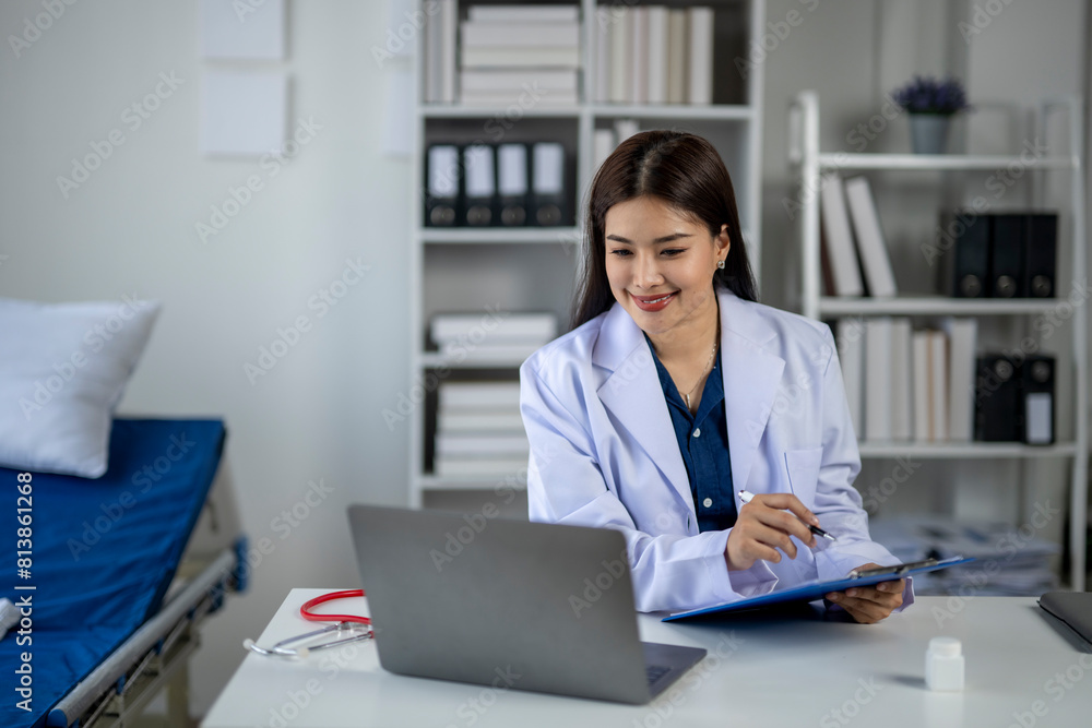 A woman in a white lab coat is sitting at a desk with a laptop and a clipboard A woman in a white lab coat is sitting at a desk with a laptop and a clipboard