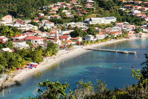 Village tropical côtier avec plage, ponton, église et baigneurs dans un lagon turquoise et émeraude. Anses d'Arlet, Martinique photo
