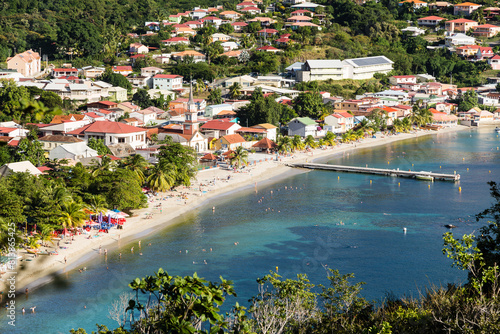 Depuis un point haut village tropical côtier avec plage, ponton, église et baigneurs dans un lagon turquoise et émeraude. Anses d'Arlet, Martinique