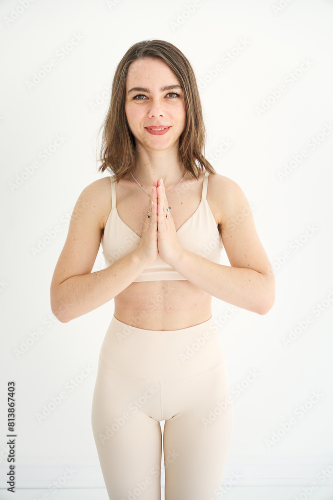 Fototapeta premium Close-up of a Yoga girl standing in a yoga pose with hands in prayer. She is smiling and looking into the camera