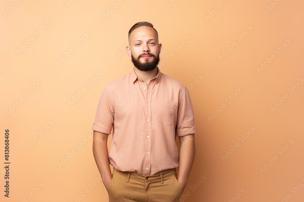 Fototapeta premium A man with a beard and a pink shirt is standing in front of a yellow wall
