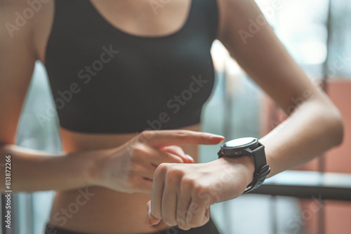 Close-up image of woman checking her smartwatch and counting calories burned during a workout session, Happy runner checking heart rate on wristwatch after exercising outdoors. © oatawa