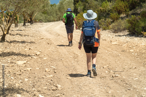 Unrecognizable couple hiking ona dusty path, ona hot summer day.