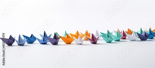 Copy space image of origami boats arranged in a group against a white backdrop