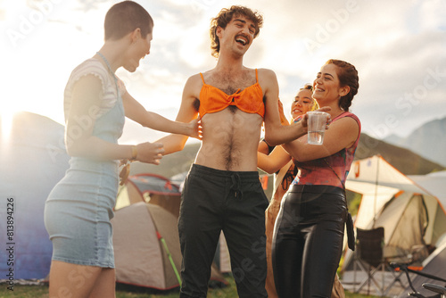 Happy man wearing a bikini bra and having fun with his friend at festival camp photo