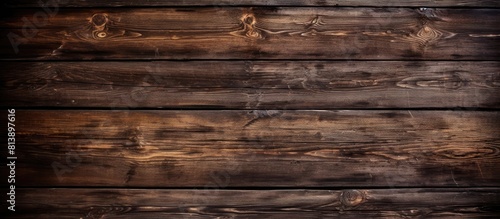 Top view of a background image showing dark brown wooden planks with scratches and stains from an old burnt table The texture of the wood is visible featuring pine and oak boards Ample copy space