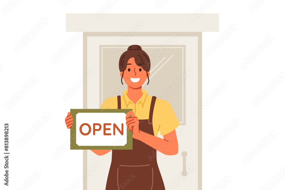 Woman waiter shows inscription open standing near door of restaurant and inviting to become visitor. Hospitable girl waiter or owner of own small business in catering industry, dressed in apron