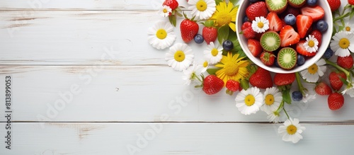A top down view of a white table adorned with a vibrant arrangement of summer flowers and a bowl overflowing with fresh strawberries Ample space for additional images