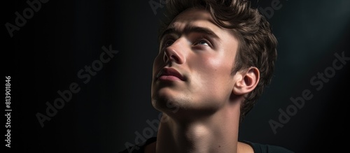 A pensive young man with a casual demeanor gazes upward in a close up portrait leaving adequate empty space in the image for copy. Copy space image. Place for adding text and design © Ilgun