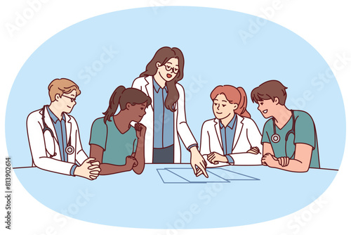 Clinic staff meeting, with doctors sitting at table and head physician giving instructions to medical workers. Men and women working in clinic choosing tactics for treatment of patient