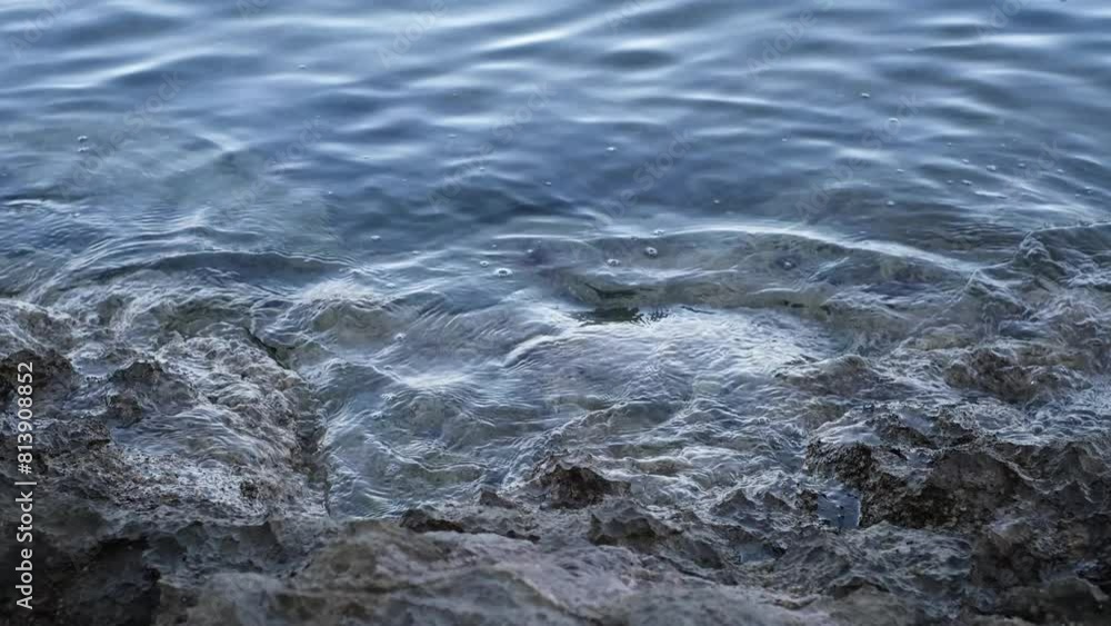 Calm ripples or waves crashing on sharp rocks. Continuously changing transparent sea or ocean surface with reflections and little bubbles. Abstract meditative slow motion of crystal clear water. Calm ripples or waves crashing on sharp rocks. Continuously changing transparent sea or ocean surface with reflections and little bubbles. Abstract meditative slow motion of crystal clear water.