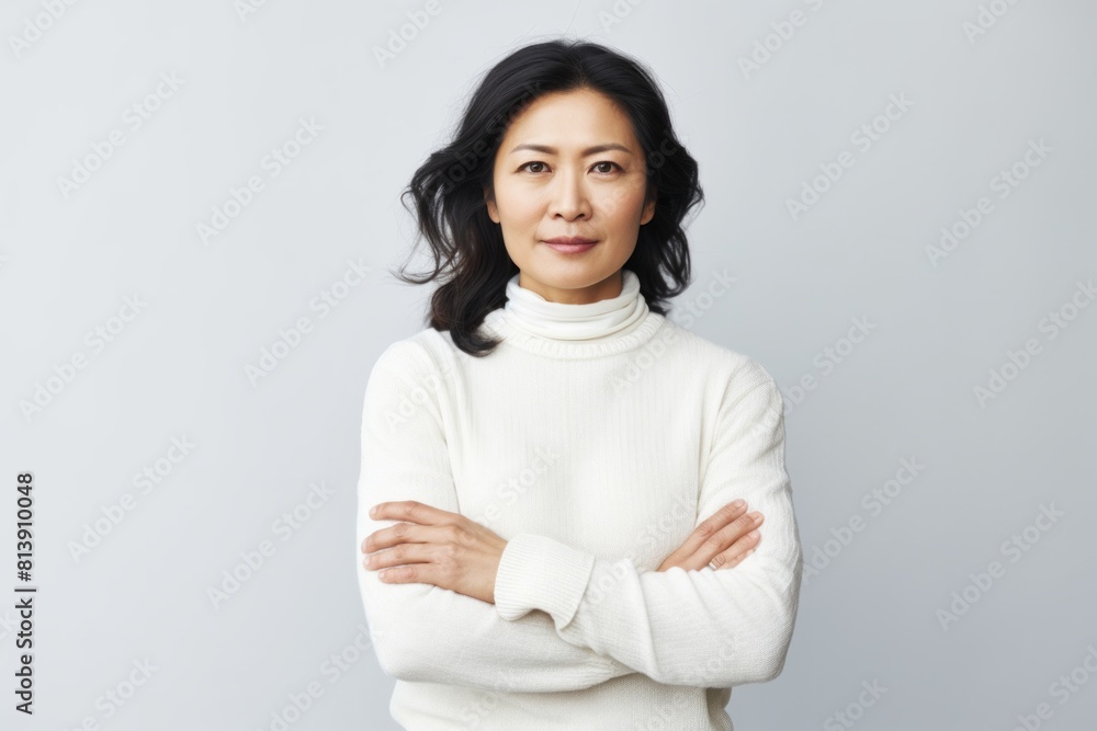 Portrait of a content asian woman in her 40s with arms crossed over white background Portrait of a content asian woman in her 40s with arms crossed over white background