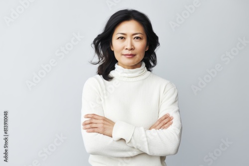 Portrait of a content asian woman in her 40s with arms crossed over white background