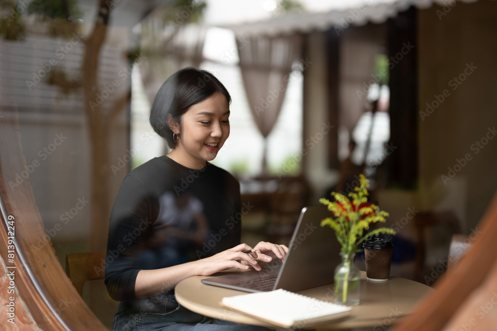 A woman is sitting at a table with a laptop and a notebook A woman is sitting at a table with a laptop and a notebook