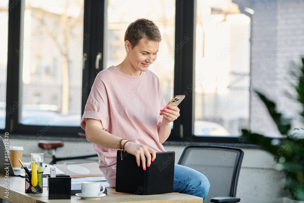 Dedicated businesswoman engrossed in her smartphone while sitting at a table. Dedicated businesswoman engrossed in her smartphone while sitting at a table.