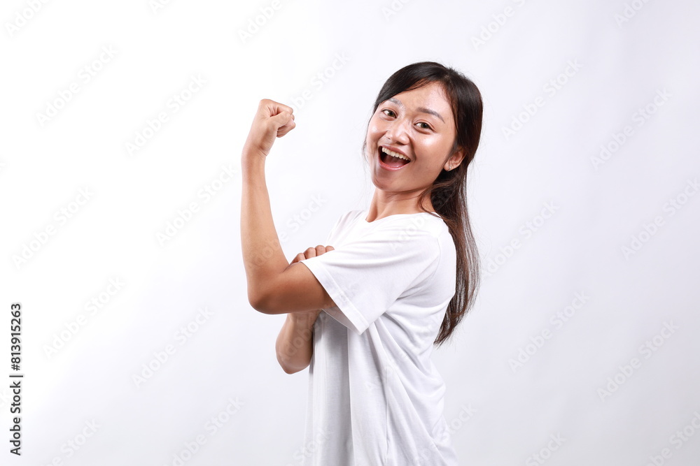 Side view young strong woman in casual showing biceps muscles on hand isolated on white background Side view young strong woman in casual showing biceps muscles on hand isolated on white background