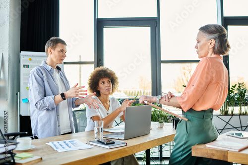 A group of hard-working, diverse businesswomen are gathered around a table, collaborating in an office setting.