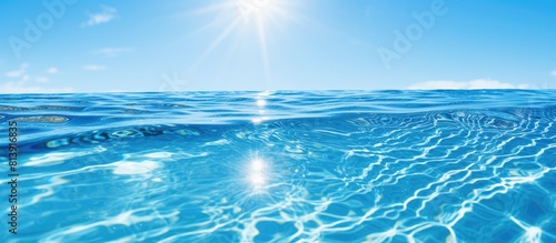 A serene outdoor swimming pool with crystal clear blue water reflects the sun s rays creating a captivating sun flare on its surface The backdrop showcases the mesmerizing blue water embellished with photo