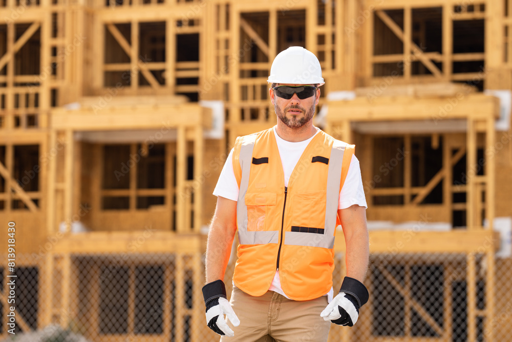 roofer builder working on roog structure of building on construction site. handsome young male builder in hard hat smiling at camera. Construction Worker on Duty. Contractor and the Wooden House Frame roofer builder working on roog structure of building on construction site. handsome young male builder in hard hat smiling at camera. Construction Worker on Duty. Contractor and the Wooden House Frame