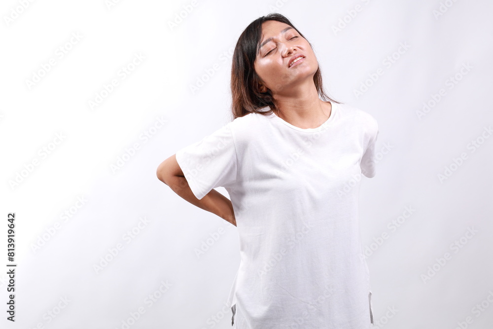 Back pain muscle stress and strain concept. Stressed young Asian woman in casual massaging her back. Isolated on white background Back pain muscle stress and strain concept. Stressed young Asian woman in casual massaging her back. Isolated on white background
