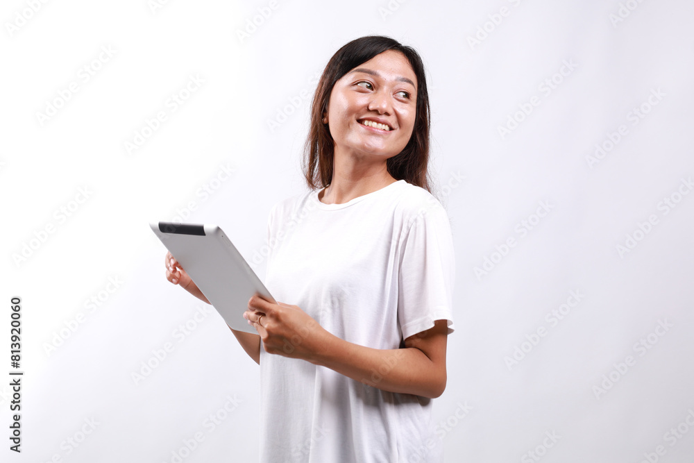 Smiling busy young asian college student woman using tablet computer, happy student woman in casual looking empty space standing over white background Smiling busy young asian college student woman using tablet computer, happy student woman in casual looking empty space standing over white background