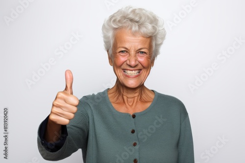 Portrait of a cheerful woman in her 50s showing a thumb up over white background
