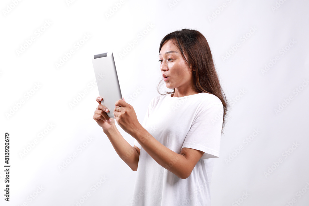Portrait of young asian woman looking at digital tablet with surprised, shocked face, side view. Isolated on white Portrait of young asian woman looking at digital tablet with surprised, shocked face, side view. Isolated on white