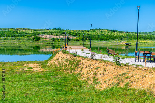 A view along the top of a jetty on the shoreline of a lake at Belsh lakes in Albasan county, Albania in summertime