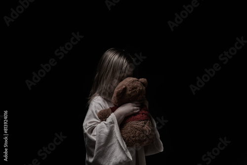 Sad little girl embracing her teddy bear - feels lonely - if you are small girl teddy bear is willing to be your best friend - vintage filter applied
