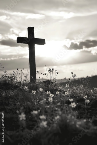 A black and white photo of a Christian cross in a field with wildflowers, creating a stark yet hopeful contrast