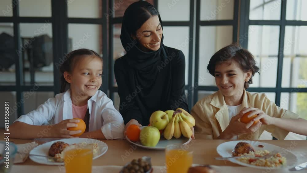 Arabian family from Dubai having lunch together in a cozy apartment. Kids with traditional parents wearing emirati kandura and abaya. Arabian family from Dubai having lunch together in a cozy apartment. Kids with traditional parents wearing emirati kandura and abaya.
