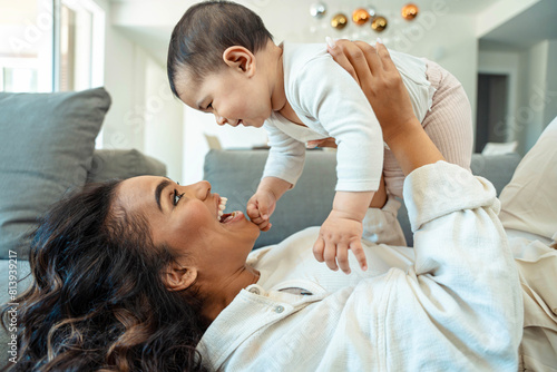 Happy black mother playing with daughter lying on sofa - Delightful mom relaxing with baby indoors - Family and childhood life style concept