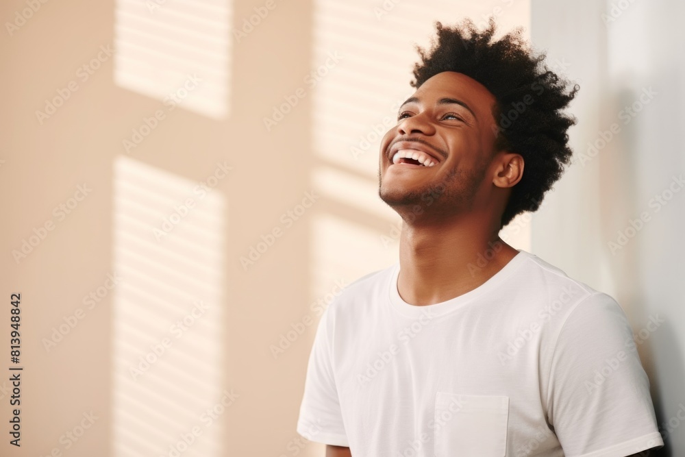 Portrait of a glad afro-american man in his 20s laughing while standing against modern minimalist interior Portrait of a glad afro-american man in his 20s laughing while standing against modern minimalist interior