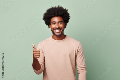 Portrait of a blissful afro-american man in his 20s showing a thumb up on modern minimalist interior