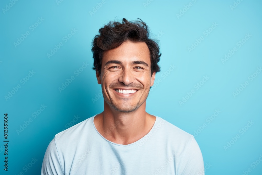 Portrait of a blissful man in his 30s smiling at the camera isolated in pastel blue background Portrait of a blissful man in his 30s smiling at the camera isolated in pastel blue background
