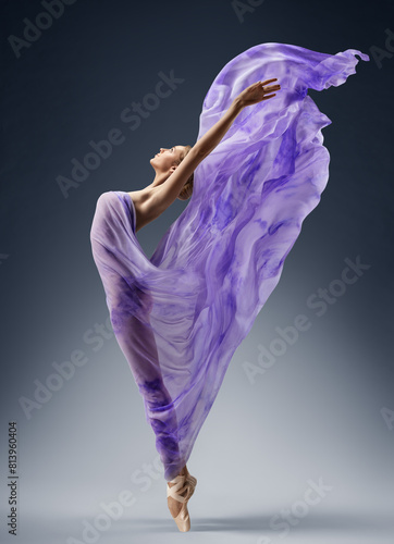 Ballerina in Purple Silk Dress flying on Wind. Ballet Dancer in waving Fantasy Gown over Gray background. Carefree Beautiful Woman dancing. Vitality and Creativity Concept