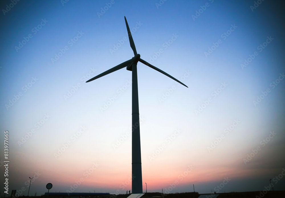 Wind turbine silhouette against a blue sky. View from the bottom point. Wind turbine silhouette against a blue sky. View from the bottom point.