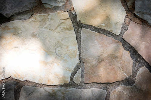Decorative masonry wall. Light stone texture background. Sunny day