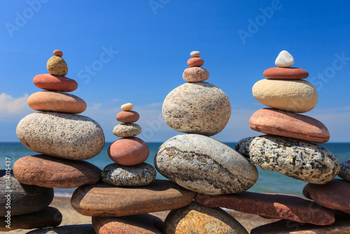 Four Rock zen pyramids of colorful pebbles standing on the beach, on the background of the sea. Concept of balance