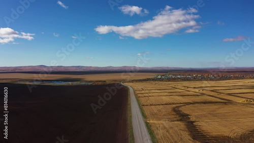 Highway between arable land and farmland on a sunny autumn day, aerial view